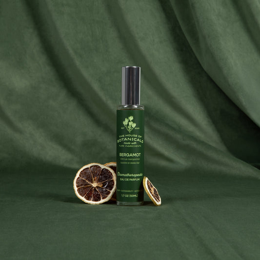 Bergamot ritual spray with dried citrus slices on a deep green backdrop