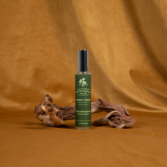 Desert Cedar ritual spray beside weathered juniper wood on an amber backdrop